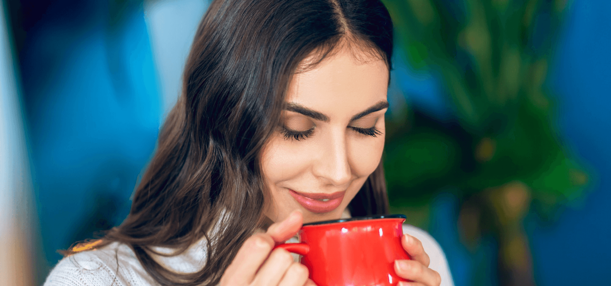 A smiling female holding a red mug